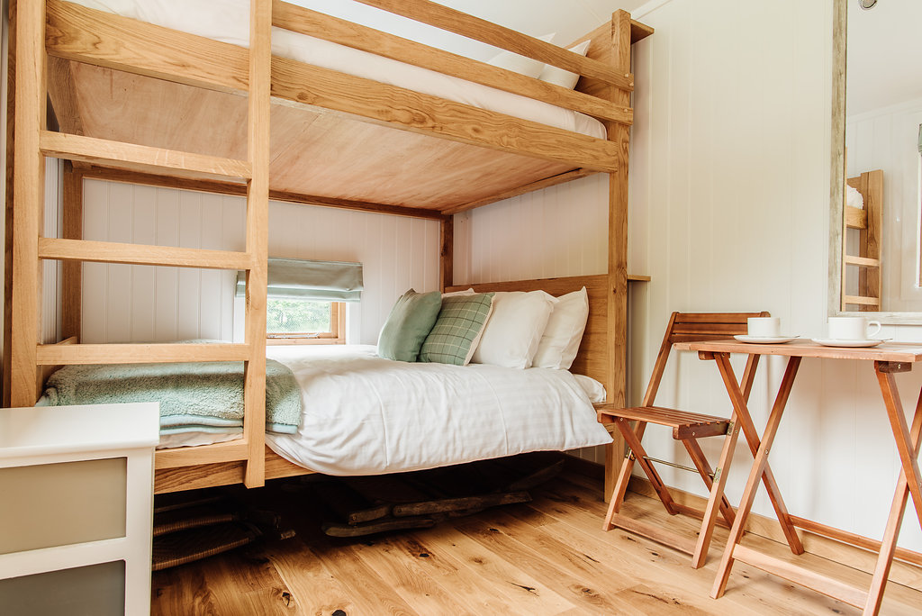 Double bunk bed with ladder and table and chairs in shepherd's hut