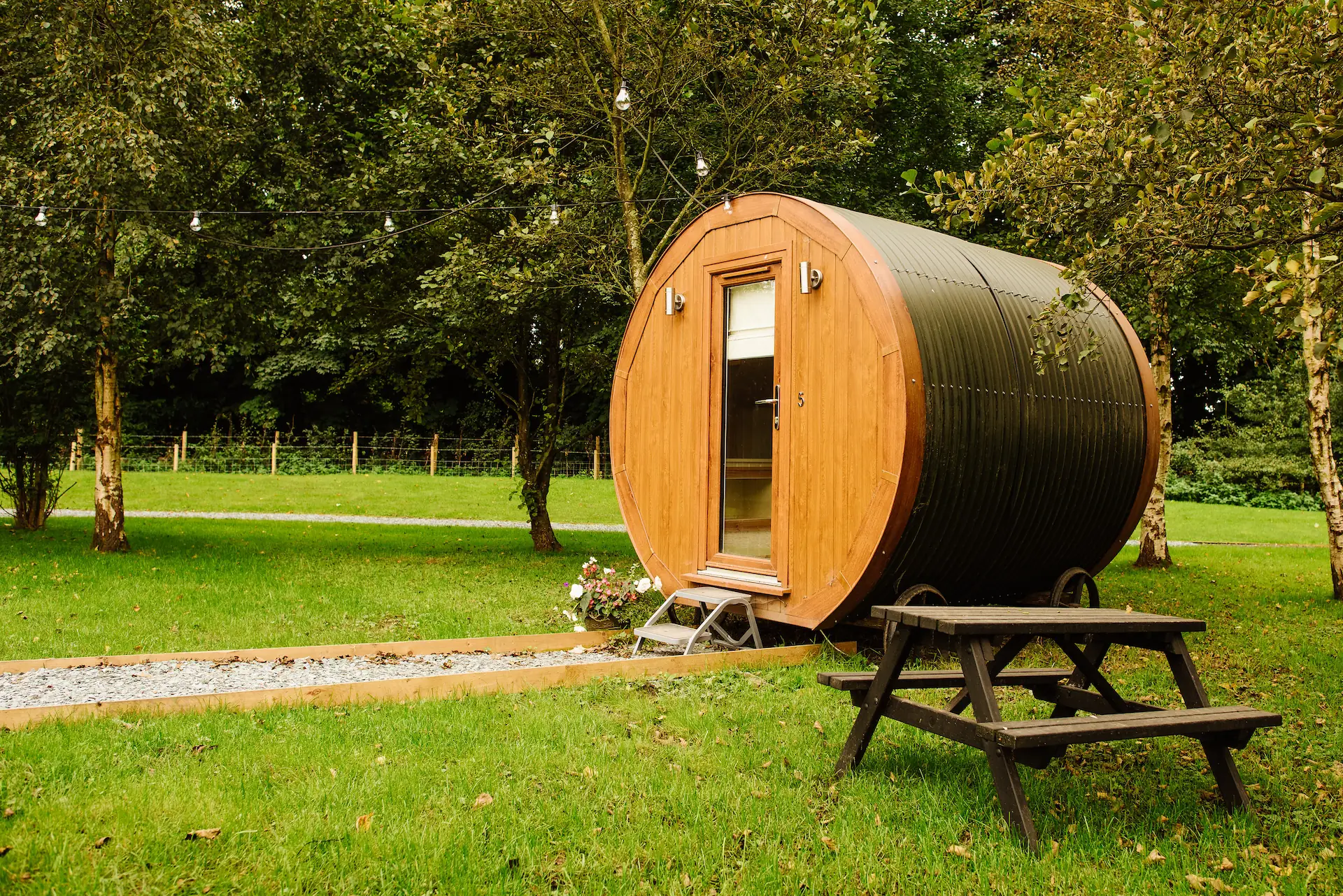 Sauna hut in grassy meadow with picnic table