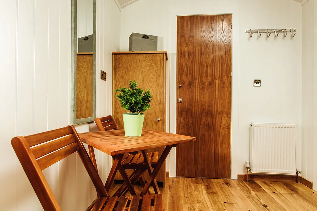 Interior of shepherd's hut with wooden floor, bright interior, and table and chairs