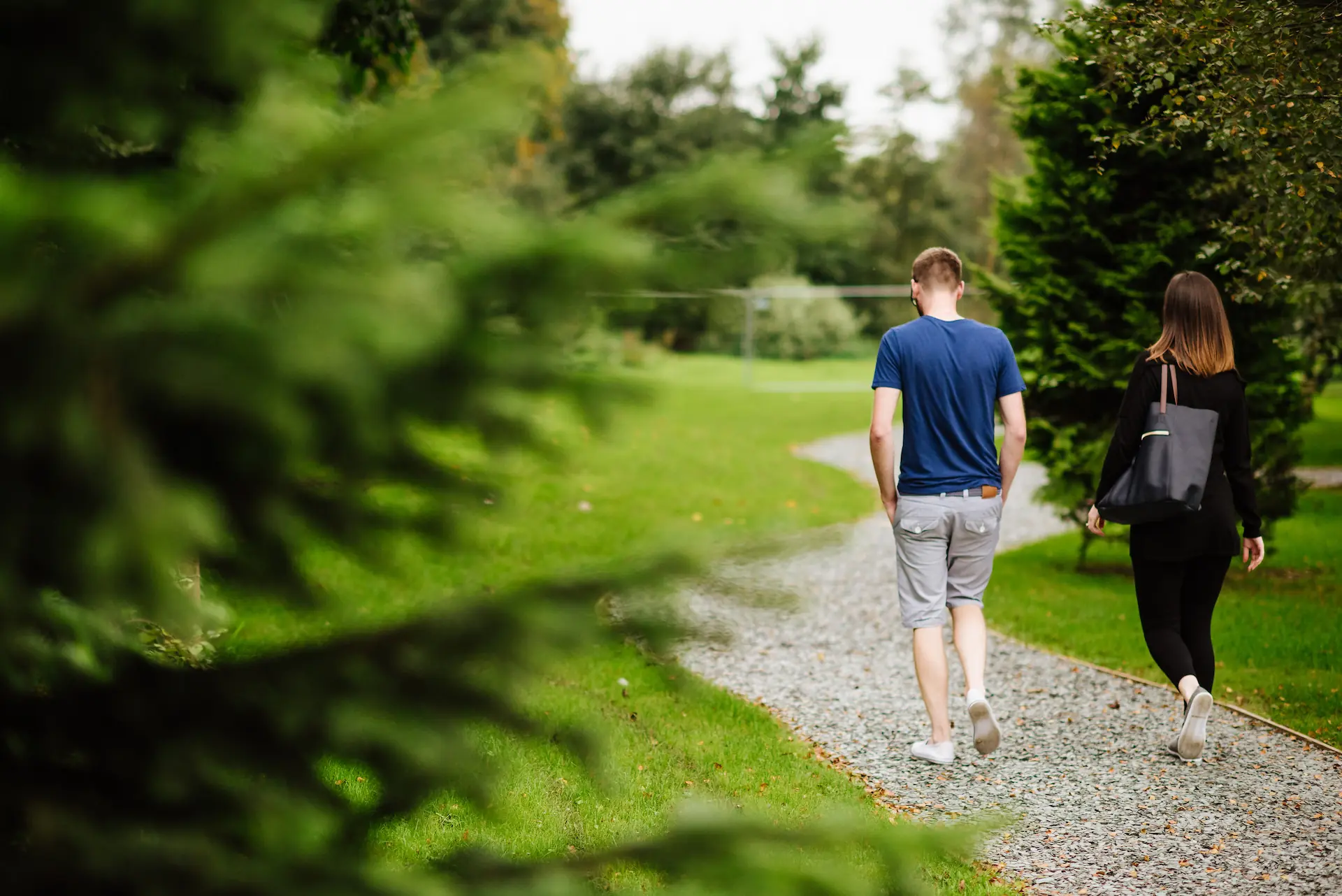 Couple walking through wooded grounds on a gravel path