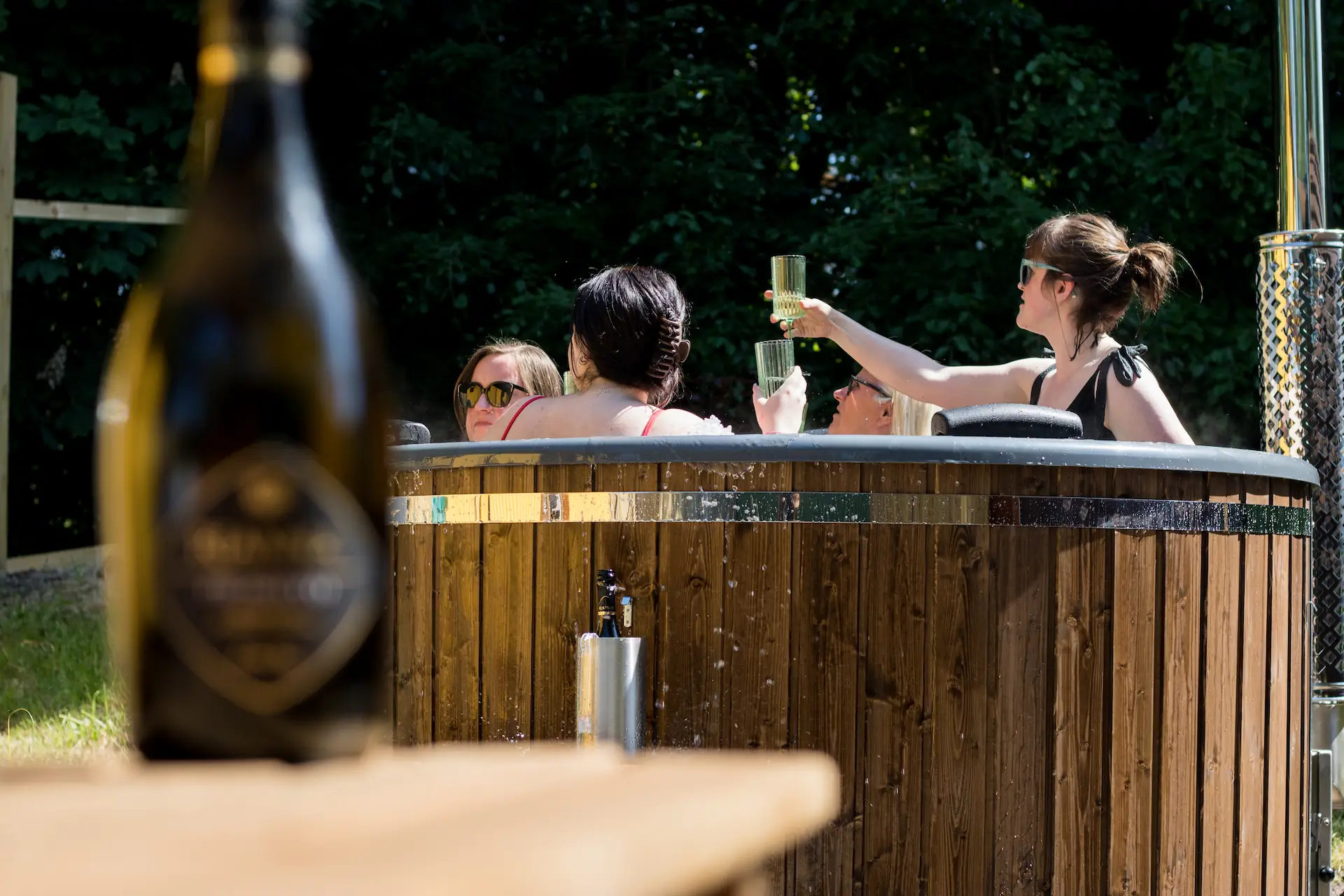 Bottle of wine with women in the background in a hot tub