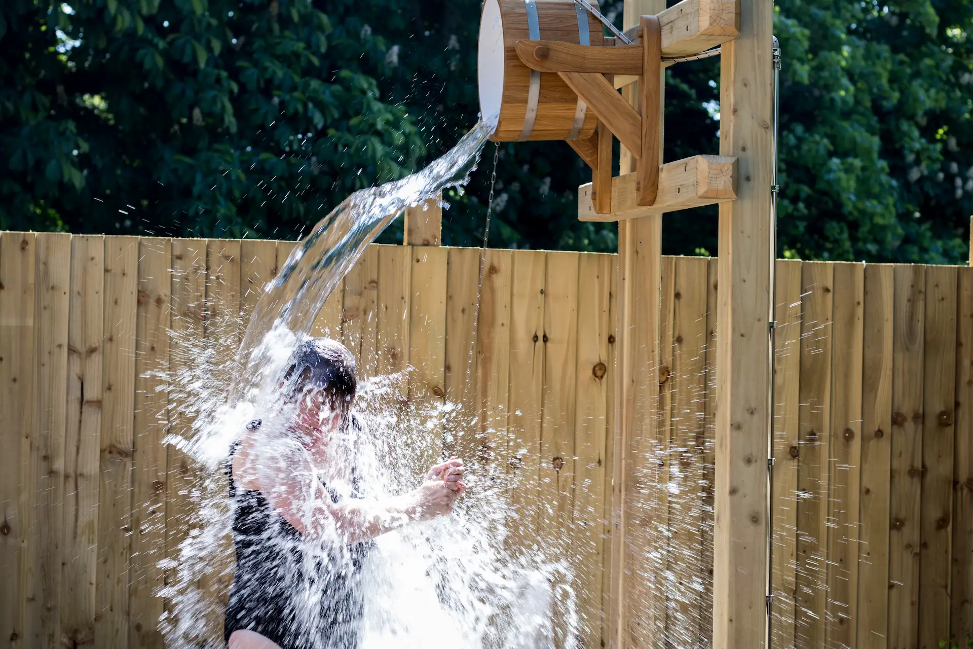 Person stood below the rushing flow of a bucket shower