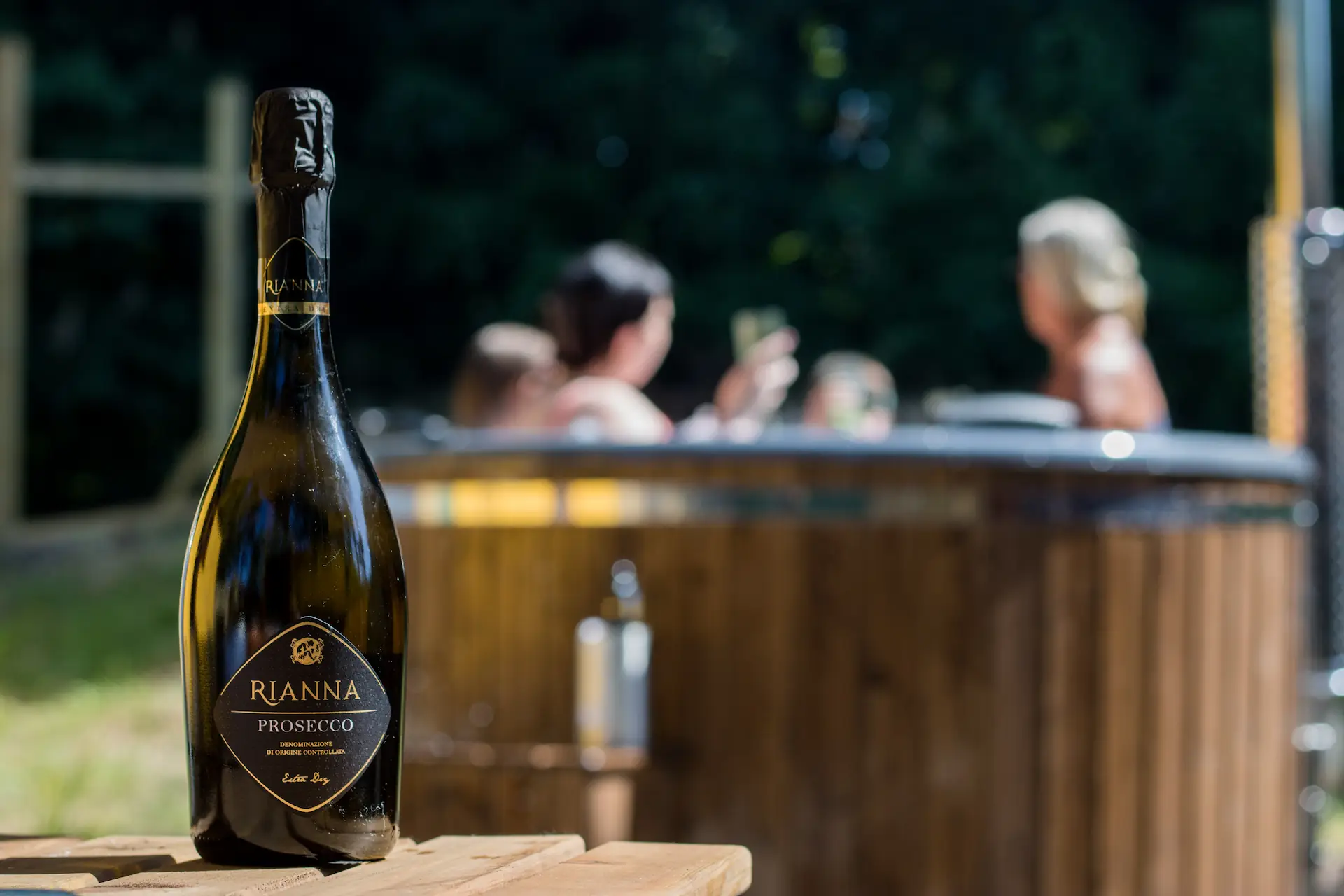 Bottle of wine with women in the background in a hot tub