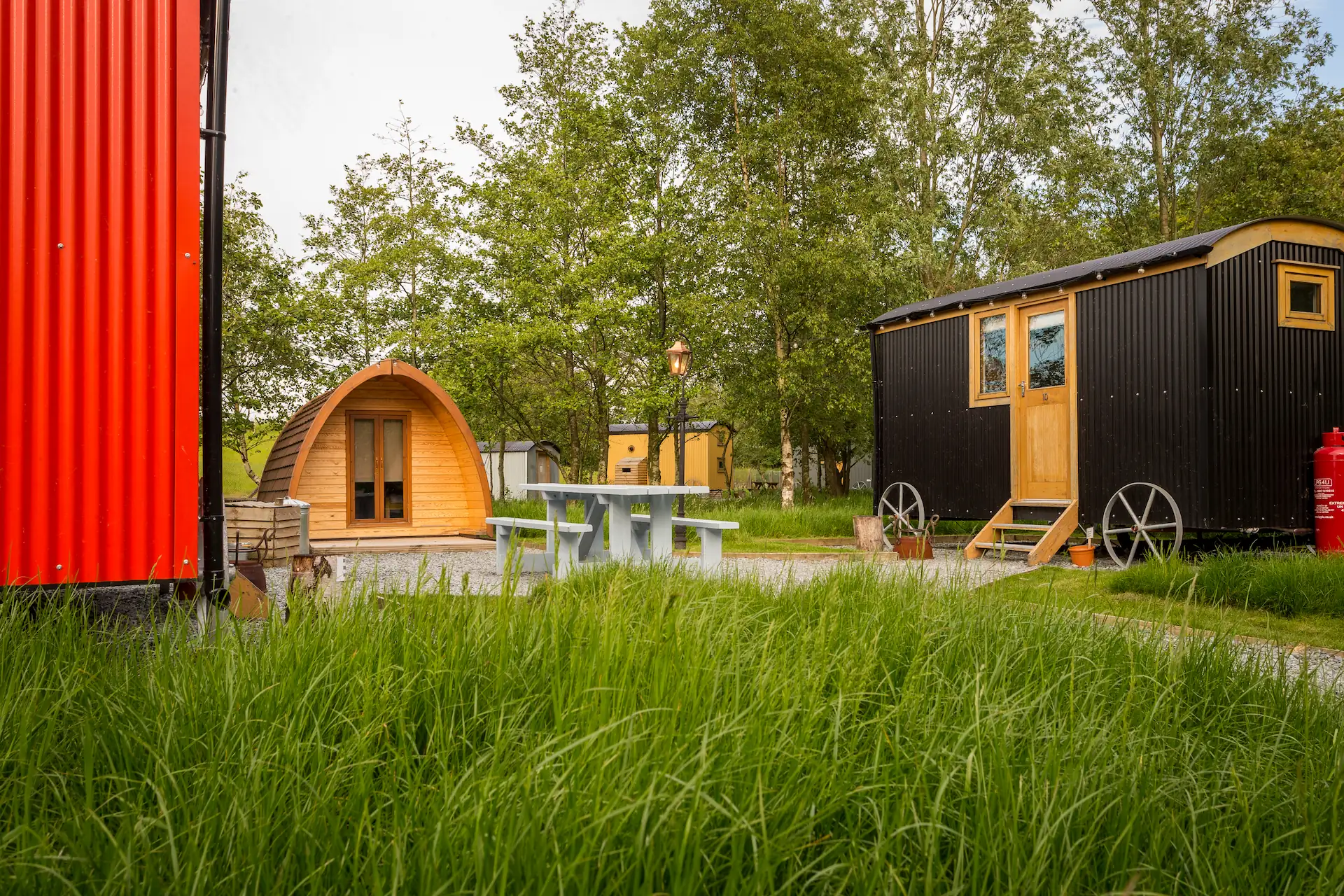Selection of shepherd's huts in grassy meadow, surrounded by trees